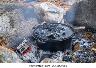 Food Baking In A Cast Iron Dutch Oven Outside Over A Smokey Open Wood Fire On An Autumn Day