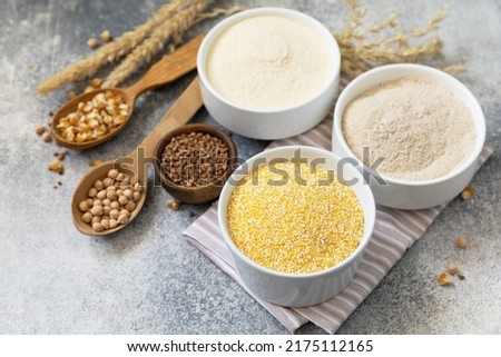 Food and baking gluten free ingredient. Cereals and flours coarse, corn flour, buckwheat flour, chickpeas flour over gray stone background. Copy space.