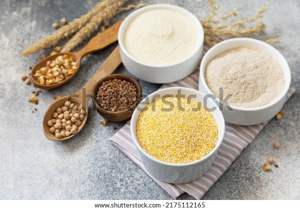 Food and baking gluten free ingredient.\
Cereals and flours coarse, corn flour, buckwheat flour, chickpeas\
flour over gray stone background. Copy\
space.
