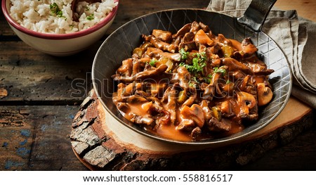Food banner of meat cut into strips. Pan with goulash stroganoff meal on rustic wooden plate
