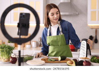 Food blogger cooking while recording video with smartphone and ring lamp in kitchen - Powered by Shutterstock