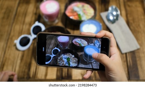 Food Blogger Making Content For Social Networks. Shooting Vegan Breakfast With Smartphone: Blueberry Smoothie Bowl With Nuts, Strawberry Smoothie Bowl With Slices Of Fruits, Pink And Blue Latte