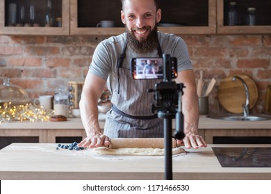 food blogger streaming live. bearded hipster man communicating with subscribers through phone camera. chef rolling out dough with a pin. - Powered by Shutterstock