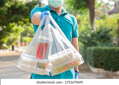  Food Boxes In Plastic Bags Delivered To Customer At Home By Delivery Man Wearing Face Mask And Wear Hygiene Gloves In Green Shirt.delivery Service During Covid19 