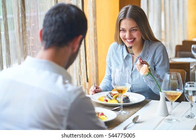 Food, Christmas, Holidays And People Concept - Smiling Couple Eating Main Course At Restaurant