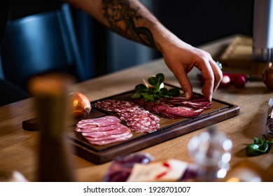 Food concept; Chef decorate ready dish with slices salami.
Young man with tattoo decorate delicious snack rustic salami with onion and cress. - Powered by Shutterstock