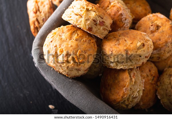 Food concept Fresh baked Homemade\
buttery, salty Ham and cheese scones on black\
background\
