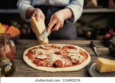 Food Concept. Fresh Original Italian Raw Pizza, Preparation In Traditional Style. Making Pizza. Female Hands Rubbed Cheese Grated On Pizza, Pizza Cooking In A Real Home Interior Lifestyle And Toning.