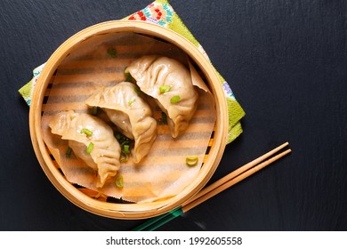 Food concept homemade Jiaozi Chinese dumpling in bamboo streamer basket on black background with copy space