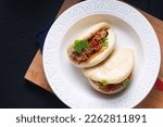 Food concept Homemade organic Pulled Beef Bao Buns or Gua Bao in white ceramic plate on black background with copy space