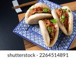 Food concept Homemade organic Pulled Beef Bao Buns or Gua Bao in sqare plate on black background with copy space