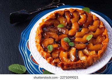 Food concept homemade tarte tatin upside down apple tart pie on black slate stone background with copy space