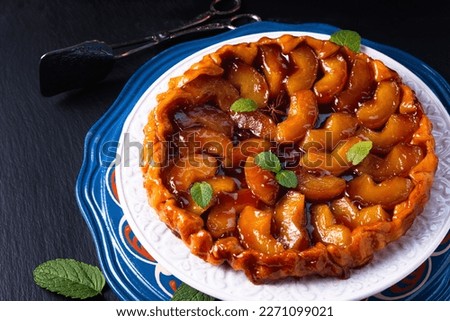 Food concept homemade tarte tatin upside down apple tart pie on black slate stone background with copy space