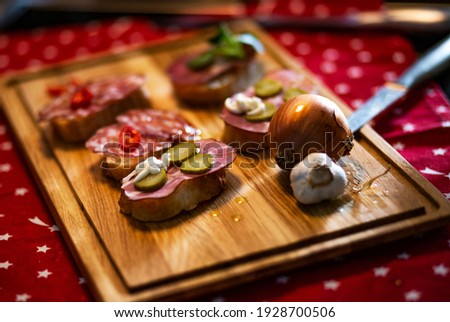 Food concept; Sandwiches with salt, slices salami and pepper.
Delicious snack rustic sandwiches, on a wooden cutting board, in a kitchen.