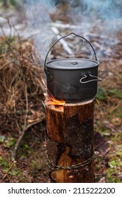 The food is cooked in the pot on Swedish Fire Log. Burning a Swedish candle, torch in winter evening.