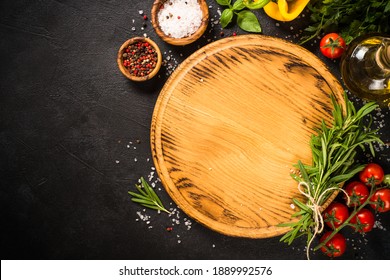 Food Cooking Background With Cutting Board, Spices, Herbs And Vegetables At Black Slate Table. Top View With Copy Space.