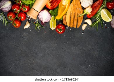 Food Cooking Background On Black Stone Table. Fresh Vegetables, Spices, Herbs And Oil. Ingredients For Cooking With Space For Your Text.