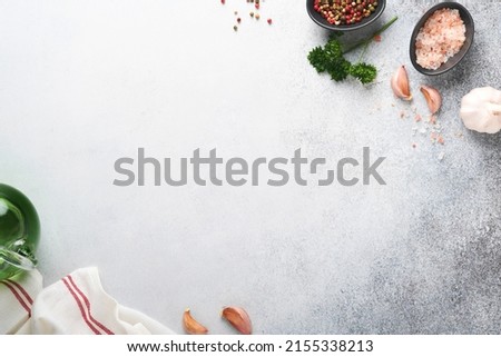 Food cooking background. Stone texture with sea salt, pepper garlic and parsley on light grey. Abstract food background. Empty space for text. Can be used for food posters, design of menu. Top view.