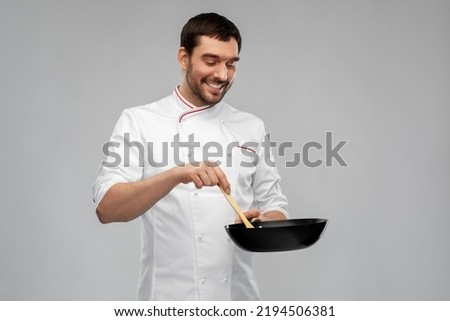 food cooking, culinary and people concept - happy smiling male chef in jacket with frying pan and spoon over grey background