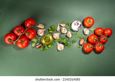 Food Cooking Preparation Background. Kitchen Table Background With Spices, Herbs, Vegetables. Parsley, Onion, Garlic, Tomatoes, Salt, Olive Oil On Dark Green Background Top View Flatlay Copy Space