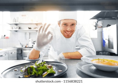 food cooking, profession and people concept - happy male chef cook with plate of soup and salad at restaurant kitchen table showing ok hand sign - Powered by Shutterstock