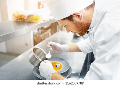 Food Cooking, Profession And People Concept - Happy Male Chef Cook Serving Plate Of Soup At Restaurant Kitchen