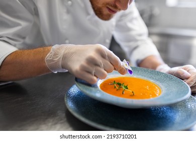 food cooking, profession and people concept - close up of male chef with flower serving plate of pumpkin cream soup at restaurant kitchen - Powered by Shutterstock