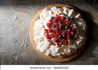 Food, Culinary, Baking And Cooking Concept - Close Up Of Pavlova Meringue Cake Decorated With Berries On Wooden Serving Board