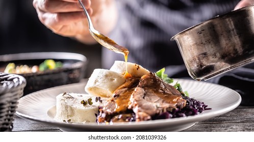 Food decorating hand of a chef pours sauce over hearty food of meat, dumplings and cabbage. - Powered by Shutterstock