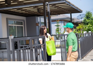 Food Deliver Asian Man In Green Uniform Give Fruit And Vegetable To Receiver Customer Front House, Fast Express Grocery Service When Crisis Coronavirus