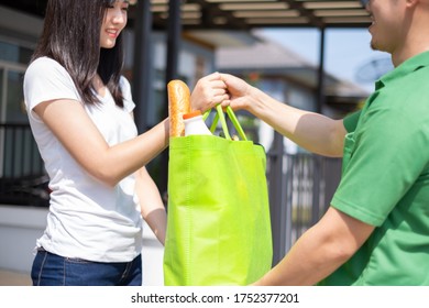 Food Deliver Asian Man In Green Uniform Give Fruit And Vegetable To Receiver Customer Front House, Fast Express Grocery Service New Normal Lifestyle Concept.