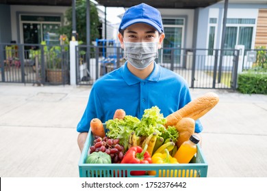 Food Deliver Asian Man Wearing Mask In Uniform Give Fruit And Vegetable To Receiver Customer Front House, Fast Express Grocery Service New Normal Lifestyle.