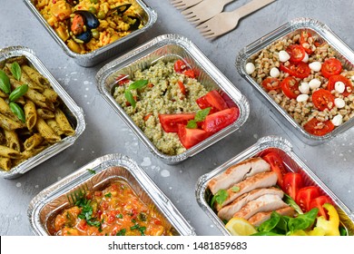 Food Delivery . Airlines Food.  Different Aluminium Lunch Box With Healthy Natural Food Tray With  Pasta Pesto, Spelt, Paella, Quinoa, Chicken Salad, Curry On Gray Table. Airline Meals And Snacks