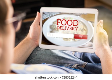 Food Delivery App On Tablet. Man Using Smart Device At Home To Make An Order From Restaurant Online. Imaginary Application, Website And Internet Store On Screen.