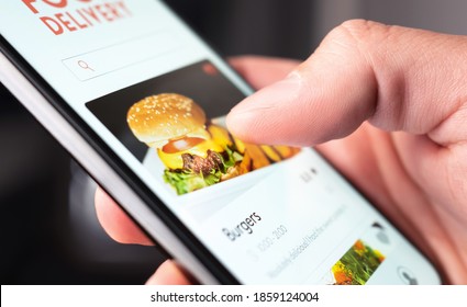 Food Delivery App Order With Phone. Online Mobile Service For Take Away Burger And Pizza. Hungry Man Reading Restaurant Menu, Website And Reviews With Smartphone. Takeout Or Fast Courier Deliver.