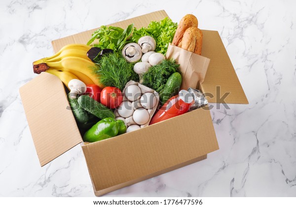 Food delivery in a box. Fruits,\
vegetables, eggs, mushrooms and bread in a box for\
delivery.