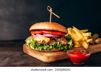 food delivery Burger hamburger with crispy bacon and potatoes fries and glass of beer on a dark background