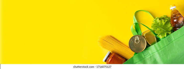 Food delivery concept on a yellow background. Biodegradable bag with foodstuffs essentials. Place for text.
