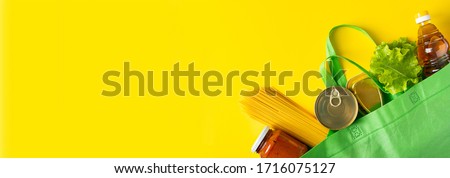 Food delivery concept on a yellow background. Biodegradable bag with foodstuffs essentials. Place for text.