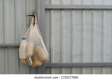 Food Delivery. A Cotton Mesh Bag For Products With Cereals, Vegetable Oil And Milk Hangs On A Fence. Zero Waste, No Plastic Purchases. Sustainable Lifestyle Concept. Recycling