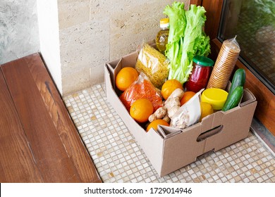 Food Delivery Or Donation Box During Covid Quarantine. Contactless Social Home Delivery, Safe Shopping In Coronavirus Pandemic. Takeout Meal. Food Box On Doorstep Near Door. Courier Home Delivery