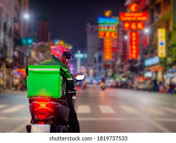 Food delivery drivers are driving deliveries to customers who ordered online at night at Street Food in Chinatown, Thailand. - Powered by Shutterstock