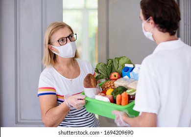 Food Delivery During Corona Virus Outbreak. Courier Wearing Face Mask Delivering Grocery Order In Coronavirus Epidemic. Safe Shopping In Pandemic. Takeout Meal. People Stockpile Food.