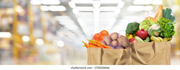 Öko-freundliche wiederverwendbare Einkaufstaschen mit Brot, Obst und Gemüse auf Supermarkthintergrund