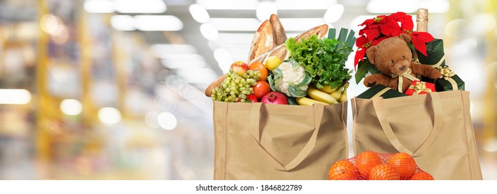 Food Delivery EcoBag With Christmas Presents On Supermarket Background. Poinsettia Leaves, Xmas Decoration, Bottle Of Wine And Teddy Bear. EcoBag With Different Holiday Food.