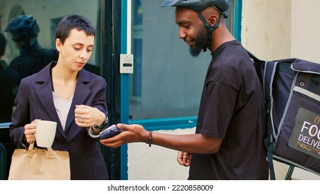 Food Delivery Employee Giving Food In Paperbag To Customer, Client Paying For Order Using Smartwach With Nfc. Male Courier Delivering Lunch Meal, Pos Contactless Payment. Handheld Shot.