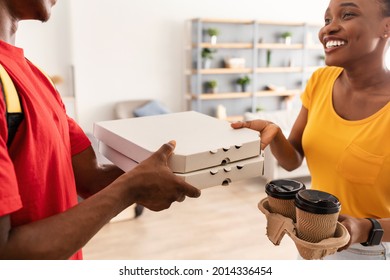 Food Delivery. Happy Black Female Receiving Pizza And Coffee From Courier Guy Standing In Doorway Of Her Home. Restaurant Delivering Service Concept. Selective Focus, Cropped