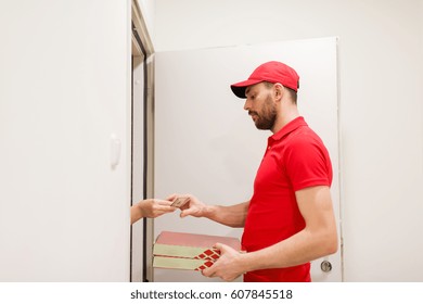 food delivery, mail and people concept - man delivering pizza in paper boxes to customer home and taking payment