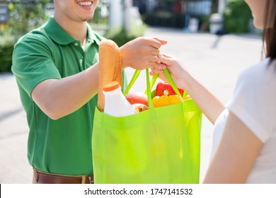 Food Delivery Man In Blue Uniform Give Fruit And Vegetable To Receiver Customer Front House, Fast Express Grocery Service When Crisis Coronavirus