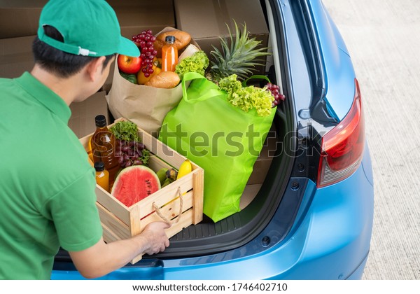 Food Delivery man giving fruit and vegetable shopping\
supermarket to receiver customer front house from truck car,\
express grocery service when coronavirus crisis covid19 new normal\
lifestyle 
